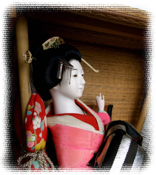 japanese antique geisha doll sitting in ancient straw carriage